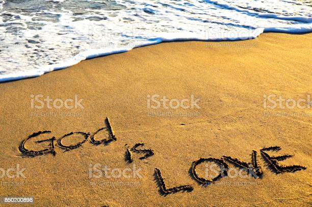 God is love text on beach and wave